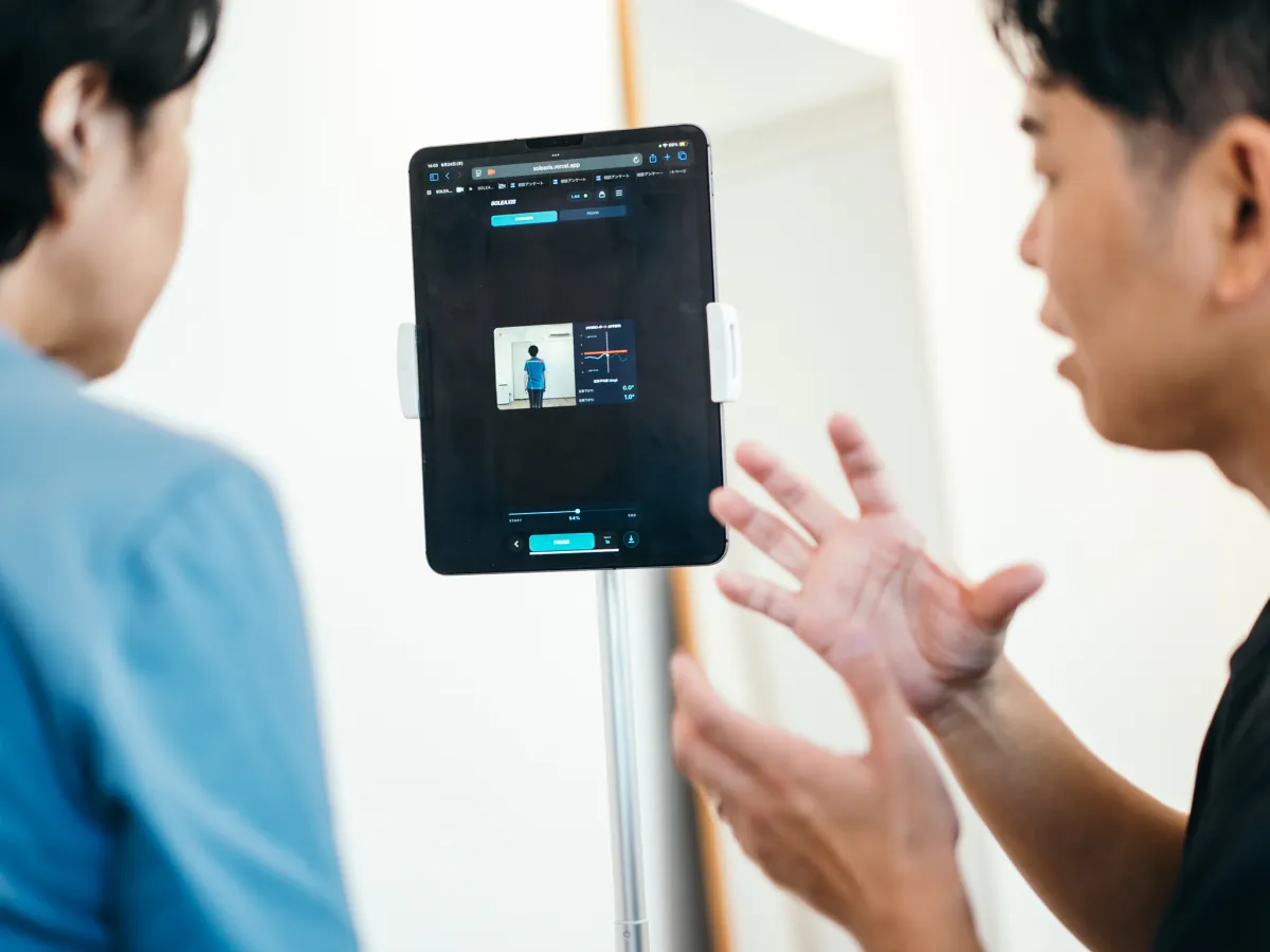 歩き方をAIで分析したタブレットの画面を見ながら、院長が説明している場面